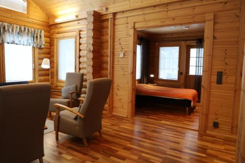 - une chambre dans une cabane en rondins avec un lit et des chaises dans l'établissement Luosto Villa D, à Luosto