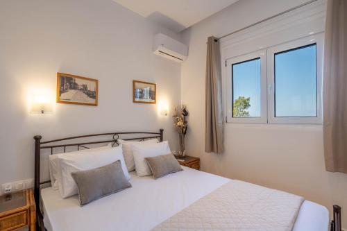 AegenitissaAmelin Villa Paradise的卧室里有一张白色的床，还有两扇窗户