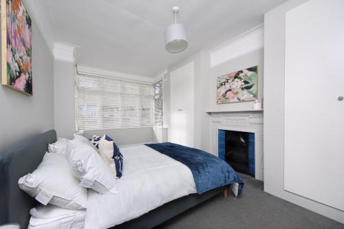 ein weißes Schlafzimmer mit einem Bett und einem Kamin in der Unterkunft West London Home in Ealing