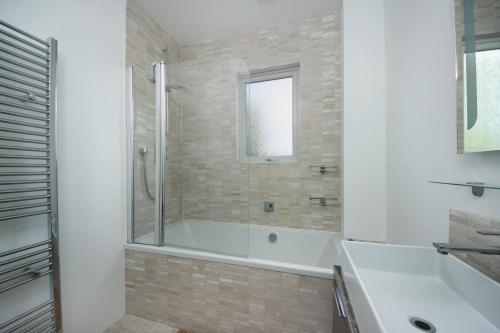 ein weißes Badezimmer mit Badewanne und Dusche in der Unterkunft West London Home in Ealing