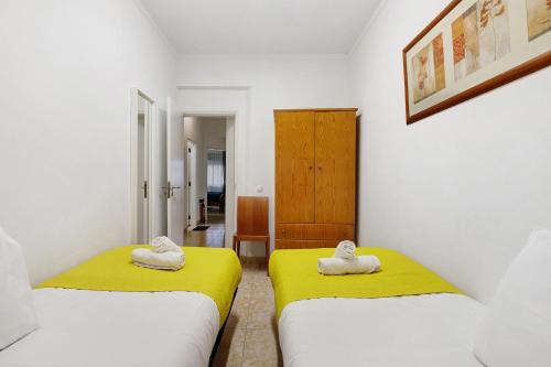 two beds in a room with yellow and white at Happy House Central Apartment in Faro