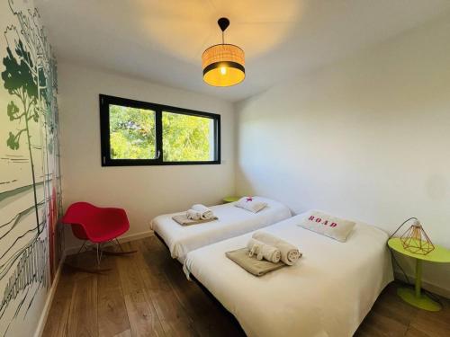 two beds in a room with a red chair and a window at Villa 8 pers à Seignosse avec piscine chauffée et clim - FR-1-791-44 in Seignosse