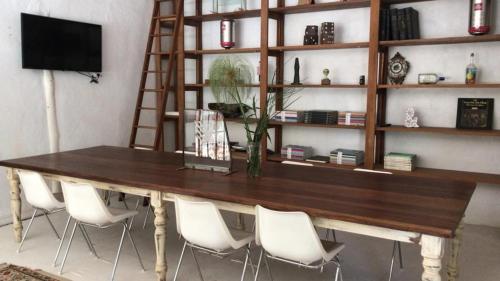 a wooden table with white chairs and a book shelf at Casa de Lujo de Tenis con Pileta Padel y Gimnasio in Garín