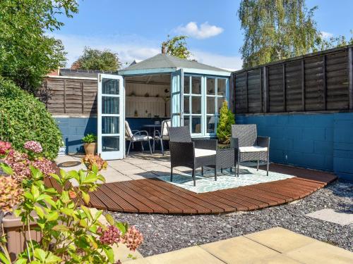 a patio with chairs and a table and a building at Beval Cottage in Abergavenny