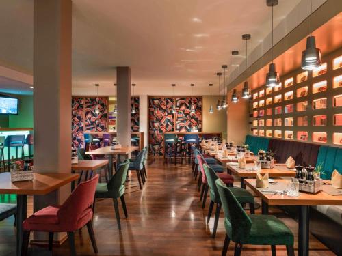 een restaurant met houten tafels en groene stoelen bij Mercure Hotel Berlin City West in Berlijn