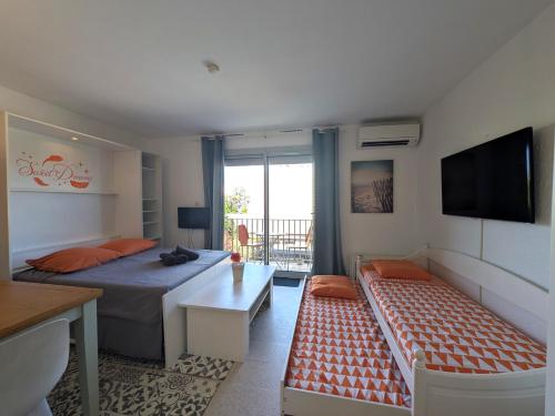 ein Schlafzimmer mit einem Bett und einer Couch und einem Fernseher in der Unterkunft STUDIO Terrasse Plage CLIM WIFI Park in Palavas-les-Flots