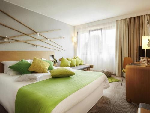 a bedroom with a large bed with green sheets and pillows at Novotel Gdansk Centrum in Gdańsk