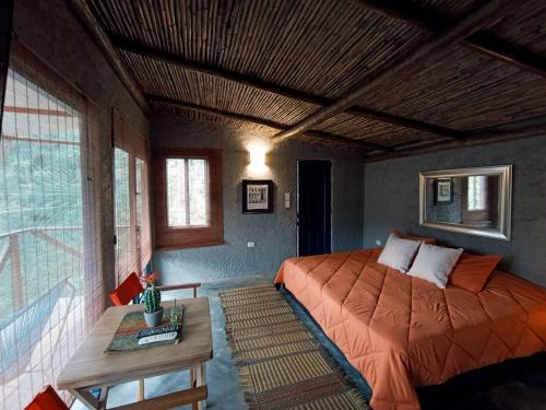 ein Schlafzimmer mit einem Bett und einem Tisch und Fenstern in der Unterkunft Mama Anzas house in a magical mountain in Villabol