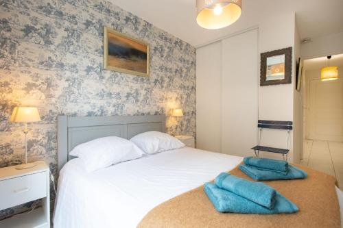 a bedroom with a white bed with blue towels on it at Les Oyats - Parking - Balcon - Plage in Le Touquet-Paris-Plage