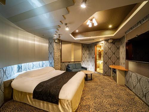 een slaapkamer met een bed en een stoel in een kamer bij Hotel LaLa (Adult Only) in Sakai