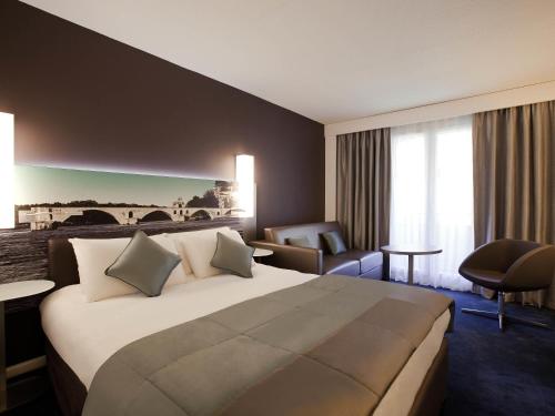 una habitación de hotel con una cama grande y una silla en Mercure Pont d’Avignon Centre, en Aviñón