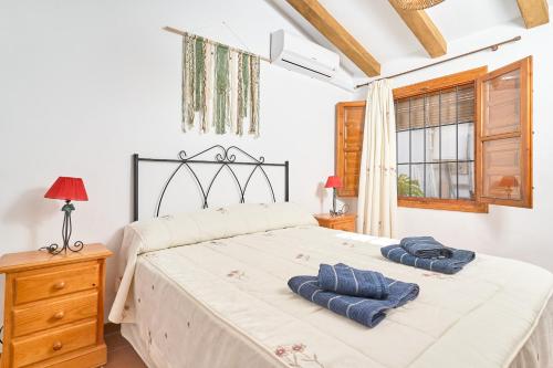 a bedroom with a bed with two blue towels on it at Cortijo A Navas in Frigiliana