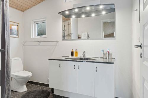 a white bathroom with a sink and a toilet at Active Coastal Holiday In Cozy Cottage in Strandlyst