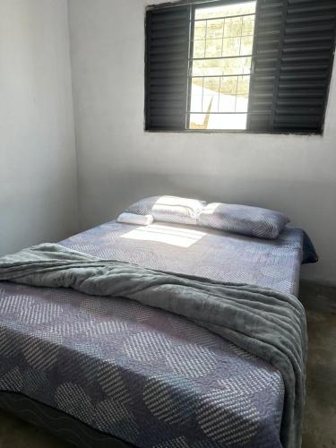 a bed with two pillows on top of it in a room at Casa LF com suíte e garagem coberta in Mineiros