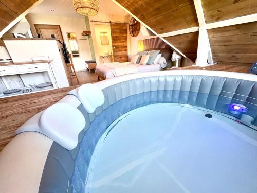 a large bath tub in a room with a bedroom at Escale en Avesnois in Croix-Caluyau
