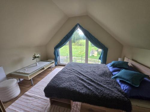 a bedroom with a bed and a large window at Domek pod Skrzycznym in Kalna