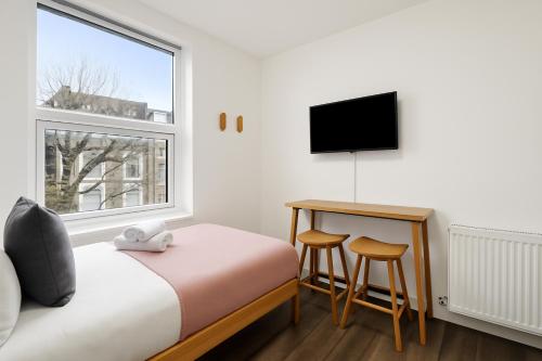 a bedroom with a bed and a desk and a window at The Little Venice Studios in London