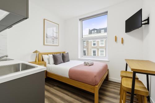 a small bedroom with a bed and a sink and a window at The Little Venice Studios in London