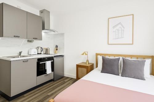 a small bedroom with a bed and a kitchen at The Little Venice Studios in London