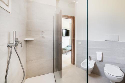 a bathroom with a toilet and a glass shower stall at VOI Arenella Resort in Arenella