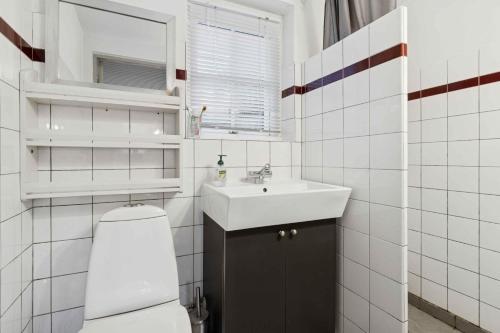een witte badkamer met een toilet en een wastafel bij Family-Friendly Beachside Holiday Home in Arnager