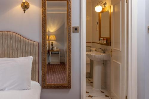 een badkamer met een spiegel, een wastafel en een bed bij Best Western Abbots Barton Hotel in Canterbury