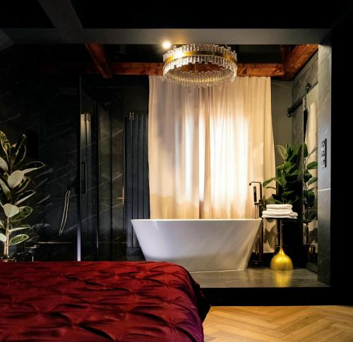 a bathroom with a bath tub and a chandelier at Apartament Plac Zabaw in Łódź