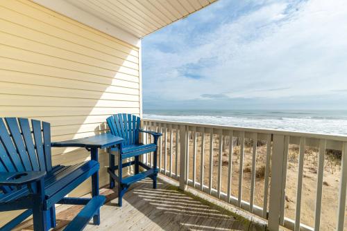 a porch with two blue chairs and the beach at Perfect Ocean View - Oceanfront Condo, Private Balcony, Community Pool in Kill Devil Hills