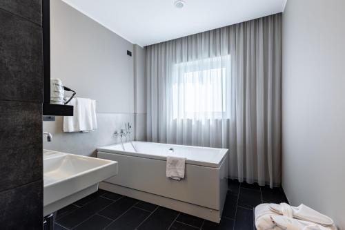 a white bathroom with a tub and a sink at H2C Hotel Milanofiori in Assago