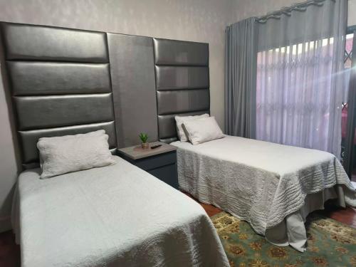 a room with two beds and a window at Lukhanya Guesthouse in Randfontein