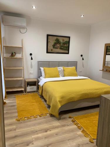 a bedroom with a bed with yellow sheets and yellow rugs at Kutal Park Inn Hotel in Përmet