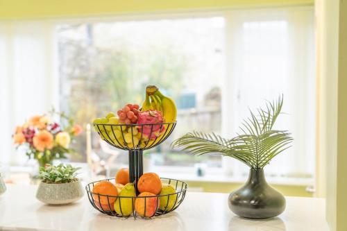 a table with a bowl of fruit and two vases at Sunnyholme - New! Yorkshire Luxurious Cottage in Hawes