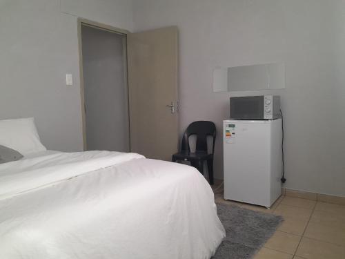 a bedroom with a white bed and a small refrigerator at Shalom Villa Guesthouse Walvis in Walvis Bay