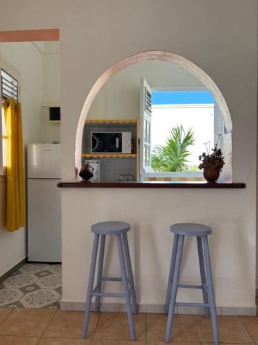 una cocina con 2 taburetes y una barra con ventana en Logement « Alpinia », en Capesterre