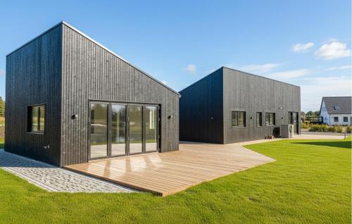 a black house with a wooden deck in a yard at 5 Bedroom Gorgeous Home In Karrebæksminde in Enø By