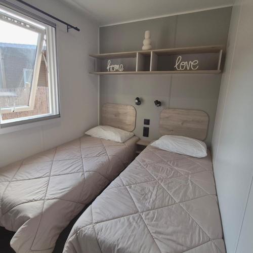 two beds in a small room with a window at Le Cocon Mobil Home à 150 m de la plage Camping 5 Etoiles Les Dunes Parc Aquatique in Torreilles