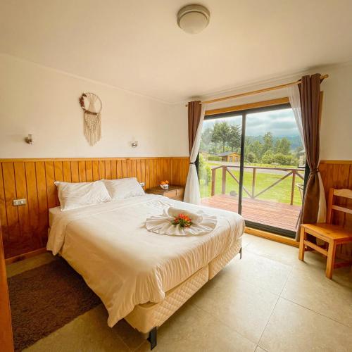 a bedroom with a bed and a large window at Cabañas Rimü - Cabañas para 8 personas in Futrono