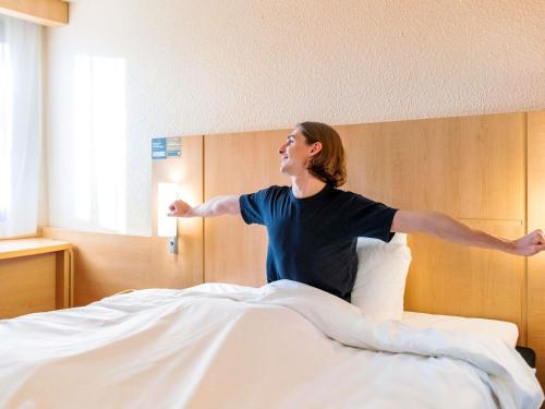 Una mujer está saltando encima de una cama. en ibis Lyon Gare Part Dieu, en Lyon
