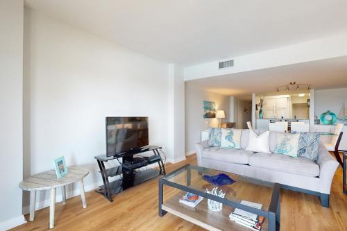 a living room with a white couch and a tv at Ocean One 215 in Hilton Head Island