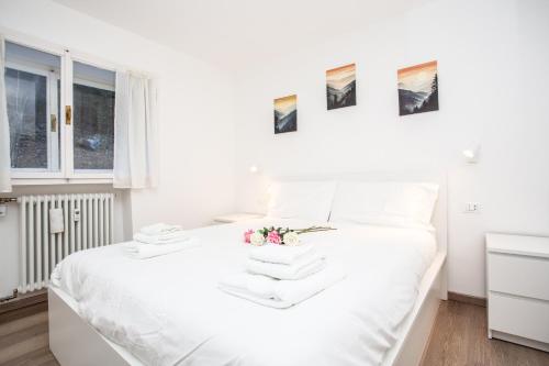 a white bed with white sheets and flowers on it at La Casa di Paola in La Thuile