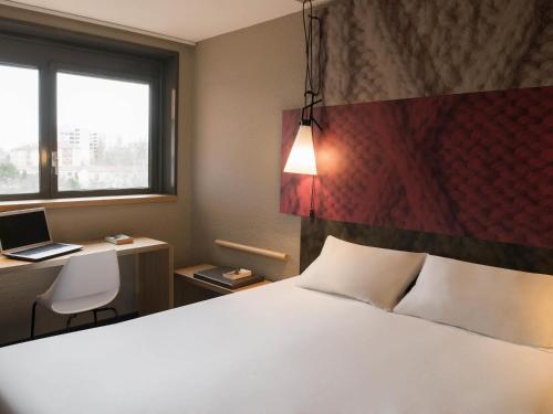 瓦朗斯宜必思瓦朗斯南部酒店的一间卧室，配有一张床和一张带笔记本电脑的书桌