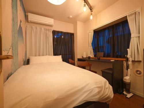 a bedroom with a bed and a desk and two windows at The Nest Koenji Cozy Stay near Station Easy Access to Shinjuku in Tokyo