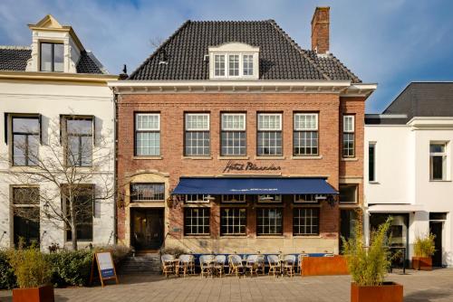 a brick building with tables and chairs in front of it at Hotel Bleecker by BHC in Bloemendaal
