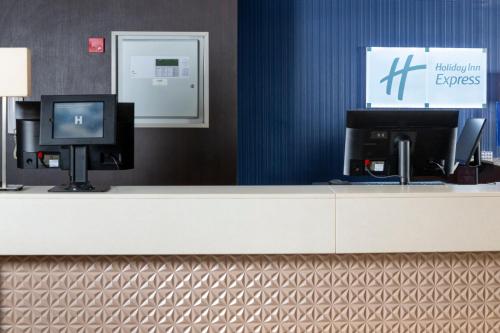 a reception desk with a tv and a monitor at Holiday Inn Express London - Wandsworth by IHG in London
