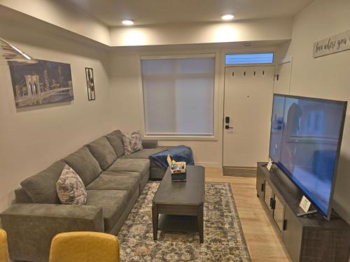 a living room with a couch and a flat screen tv at A stylish 2 BDR with a blend of cozy and peace! in Calgary