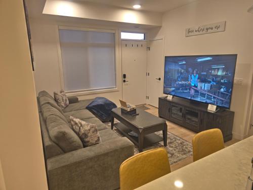 Una sala de estar con un sofá y un televisor de pantalla plana. en A stylish 2 BDR with a blend of cozy and peace!, en Calgary