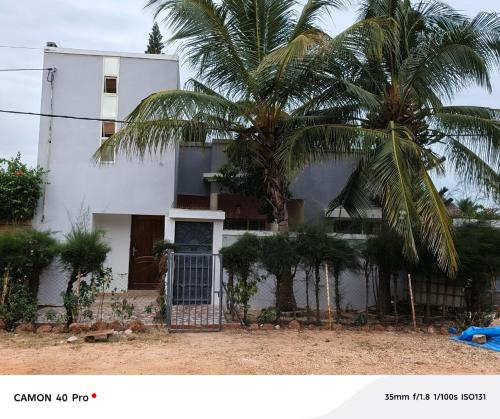 a house with two palm trees in front of it at Rabbi Chambres in Mbour