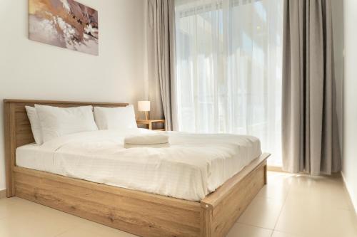 a bedroom with a bed with white sheets and a window at Sea View Modern 2BHK Apartment with Balcony in Ras al Khaimah