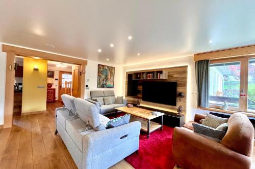 a living room with two couches and a tv at Renovated village house with terrace and quiet in Combloux
