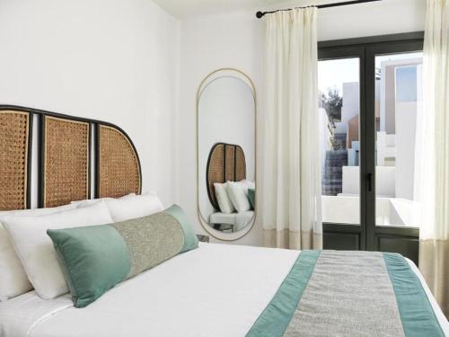 a bedroom with a large bed and a mirror at Notia Suite, Jacuzzi, Imerovigli in Imerovigli